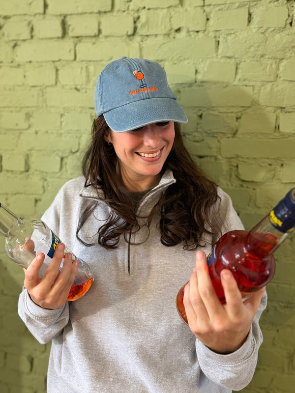 Lichtblauwe vintage pet met The Aperol Club, gedragen