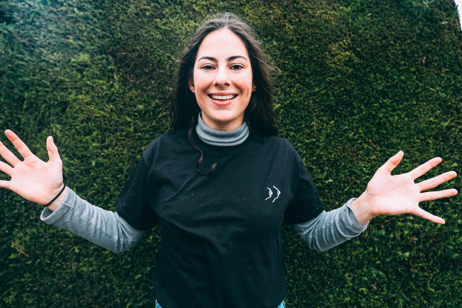 Louise rit dans un t-shirt noir avec des petits seins brodés, le premier modèle de Tice Nits