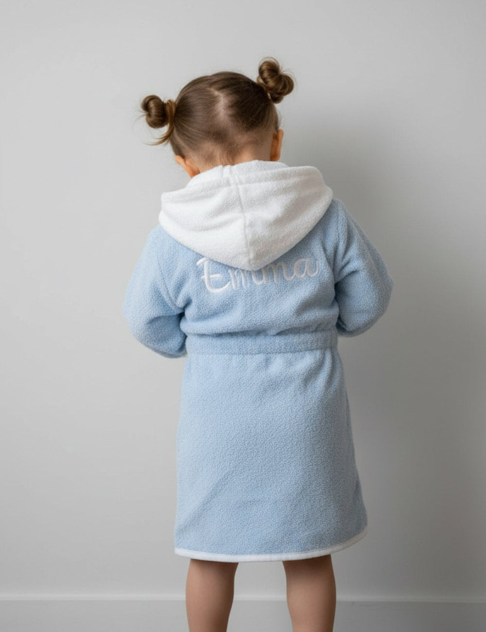 Kindje in een babybadjas met geborduurde naam op de rug, geborduurd door Tice Nits