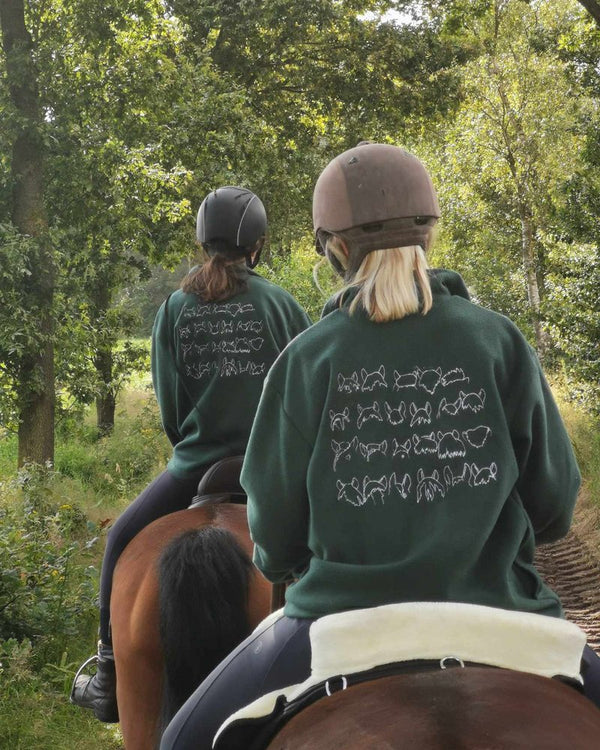 Twee ruiters in groene fleecetruien met geborduurde tekst