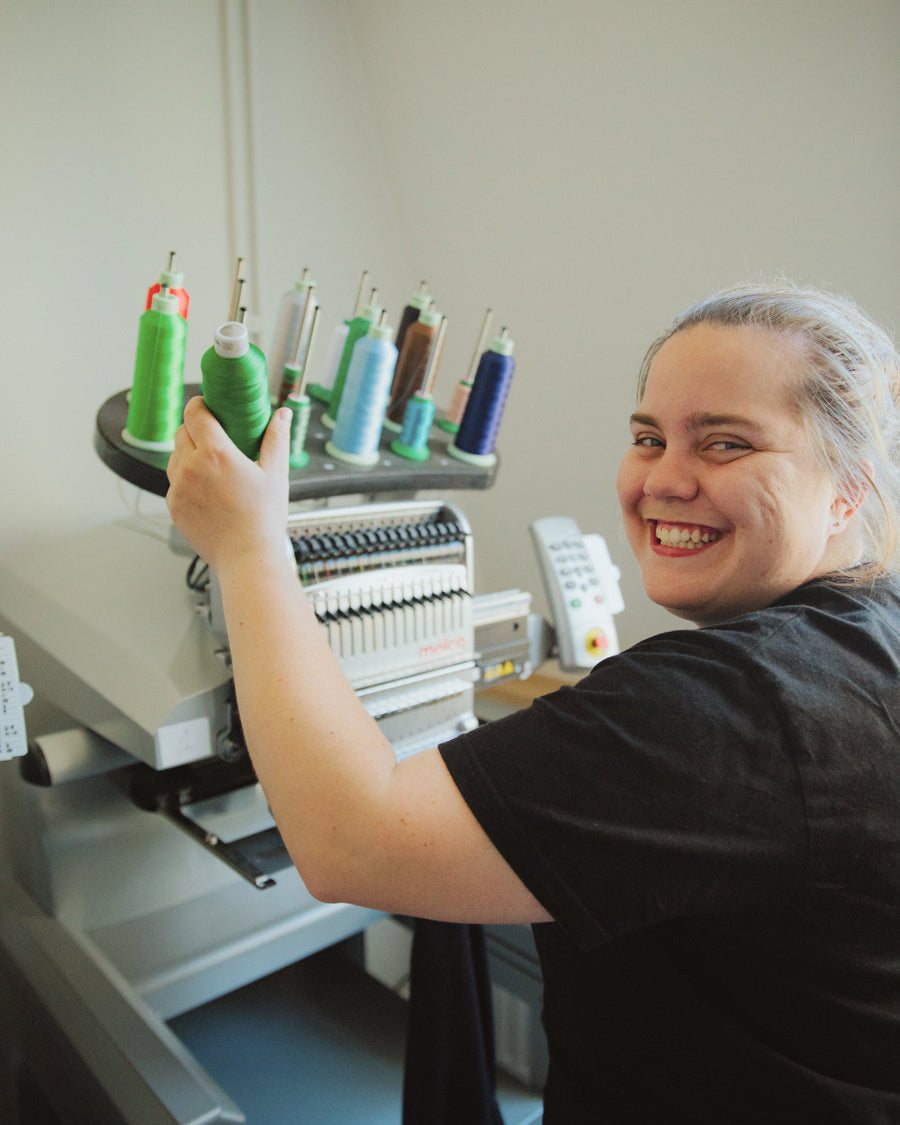 Smiling employee at the embroidery machine